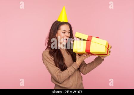 Porträt von glücklichen erstaunt Frau mit Party-Kegel Blick in Box, Auspacken Geschenk und schreien in Erstaunen, schockiert durch Geschenk, Geburt feiern Stockfoto