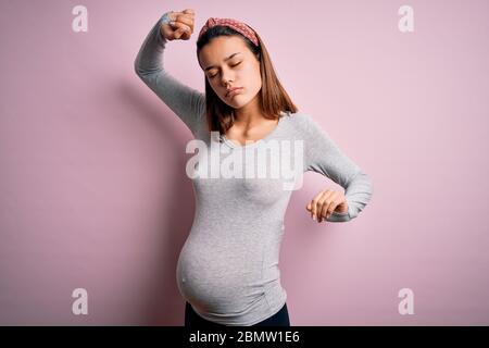 Junge schöne Teenager-Mädchen schwanger erwarten Baby über isoliert rosa Hintergrund Strecken zurück, müde und entspannt, schläfrig und Gähnen für frühe m Stockfoto