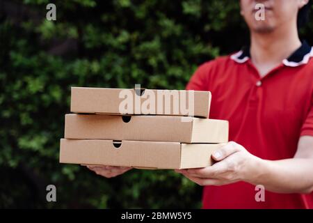 Pizza Delivery boy hält Pizzakästen im Hausgarten vor der Tür mit Kopierplatz. Stockfoto