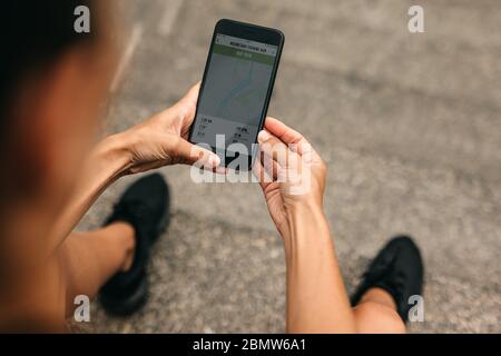 Schulteransicht einer Läuferin mit einer Fitness-App auf dem Mobiltelefon. Fitness-Frau überprüft die Zusammenfassung ihres Laufs auf dem Smartphone. Stockfoto