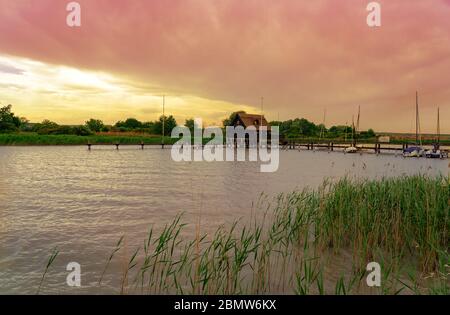 Ruhige Natur am Fertő See in Ungarn mit Holzsteg Bungalows Hütten am See und Stroh im Wasser bei Sonnenuntergang Stockfoto