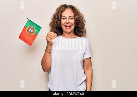 Mittelalter schöne patriotische Frau mit portugiesischer Flagge über isoliert weißen Hintergrund sieht positiv und glücklich stehend und lächelnd mit einem con Stockfoto