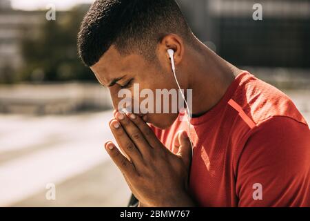 Sportler mit Ohrhörern, die sich vor dem Training im Freien konzentrieren. Fitness-Mann, der sich vor dem Training in der Stadt vorbereitet. Stockfoto