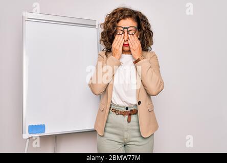 Mittlere Alter Senior Business Frau auf Seminar Präsentation von magnectic Tafel reiben Augen für Müdigkeit und Kopfschmerzen, schläfrig und müde expr Stockfoto