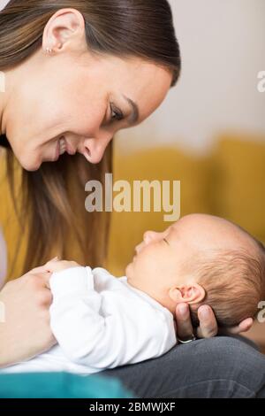 Liebevolle Mutter Cuddling Baby Sohn Auf Sofa Zu Hause Stockfoto