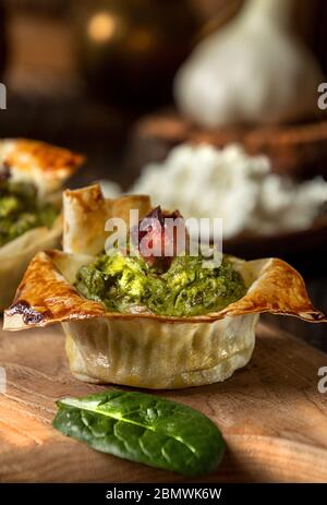 Torten mit Quark, Spinat, Ei, Champignons, Knoblauch und Speck auf Holzbrett Stockfoto