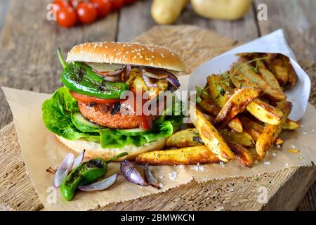 Fleischloses Street Food – köstlicher Veggie-Burger mit Sojapastete und gegrilltem Gemüse, serviert mit Kartoffelkeilen Stockfoto
