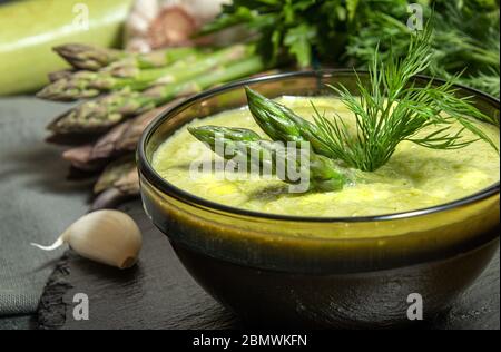 Cremige Spargelsuppe in Glasschüssel auf schwarzem Teller püriert. Nahaufnahme Stockfoto