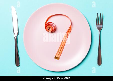 Gabel und Teller mit Maßband auf farbigen Hintergrund. Diät Konzept. Stockfoto