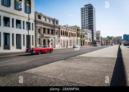 Oldtimer fahren entlang der Malecon oder Avenida de Maceo, eine breite Esplanade und Straße, die sich für 8 km entlang der Küste, Havanna, Kuba Stockfoto