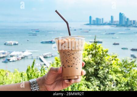 Hand, Eiskaffee und Meer mit viele Boote an der Pattaya in Thailand. Stockfoto