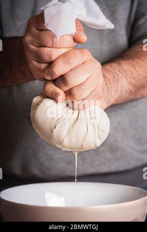 Mann bereitet Horchata durch Quetschen Milch aus Mandel und Reis Mischung in einer Schüssel. Vegane Milch nach Hause Zubereitung. Herstellung von Horchata, Sommer mexikanischen Getränk Stockfoto