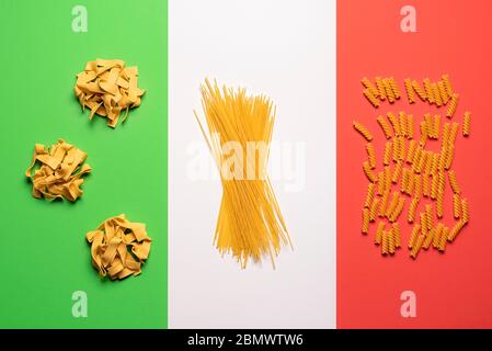 Mix aus verschiedenen Arten von Pasta, roh, auf einem Hintergrund mit italienischen Flagge Farben. Rohe Spaghetti, Fusilli und Tagliatelle. Nudelauswahl. Stockfoto