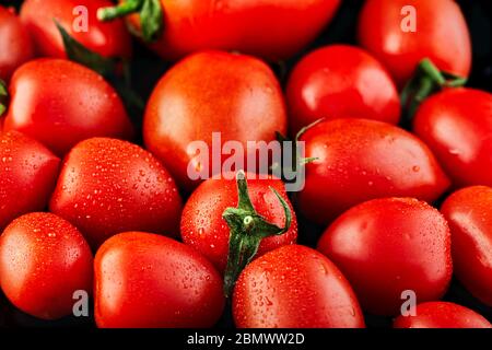 Große Tomaten und kleine Traubenkirschtomaten auf schwarzem Hintergrund. Kalorienarme Lebensmittel. Stockfoto