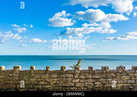 Blick aufs Meer hinter der alten Purbeck-Steinmauer an sonnigen Tagen, aufgenommen in den Pinecliff-Gärten, Branksome Chine, Poole Stockfoto