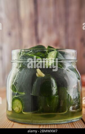 Fermentierte konservierte vegetarische Küche Konzept. Gesalzene Gurken in einem Glasgefäß auf einem hölzernen Küchentisch. Das Konzept der Konserven. Kopierbereich Stockfoto