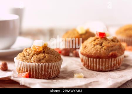 Frisch gebackene Banana Muffins mit kandierten Früchten lagen auf recyceltem Papier auf Holztisch. Frühstück am Morgen Stockfoto