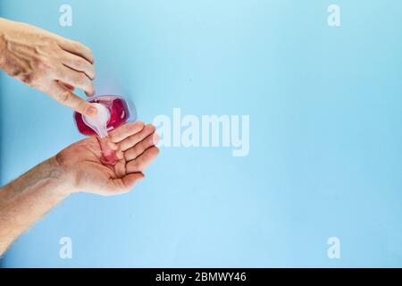 Das Konzept der Coronavirus COVID-19, wie Sie sich vor Infektionen zu schützen. Handwäsche wird auf die Hand, Maske und Tabletten gedrückt. Flach lag auf einem blauen Stockfoto