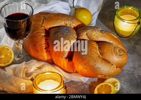 Schabbat-Challah mit weißer Serviette, mit Kerzen, einem Glas Wein und rustikalen Zitronen. Shabbat Shalom Stockfoto