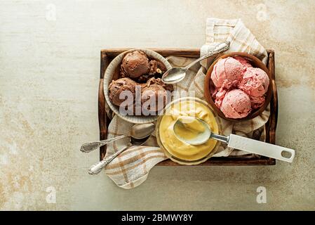 Verschiedene Eisschaufeln mit Schokolade, Erdbeere und Vanille, in Schalen geschöpft Stockfoto