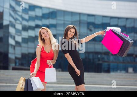 Zwei schöne Mädchen mit Einkaufstaschen zu Fuß und posiert in der Stadt Stockfoto