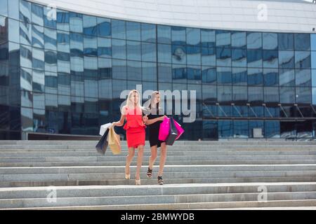 Zwei schöne Mädchen mit Einkaufstaschen zu Fuß und posiert in der Stadt Stockfoto
