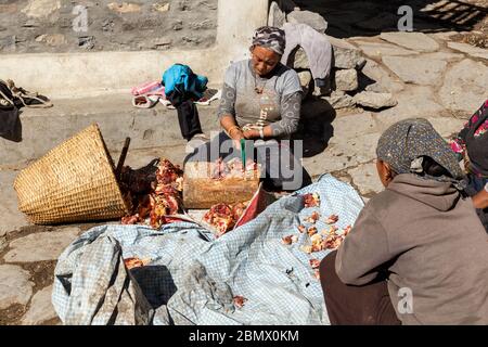 Kagbeni, Distrikt Mustang, Nepal - 19. November 2016: Nepalesische Frauen hacken Yak-Fleisch auf der Straße im Dorf Kagbeni im Himalaya. Stockfoto