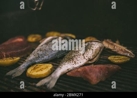 Kochen von Fisch und Kartoffeln auf dem Grill Stockfoto