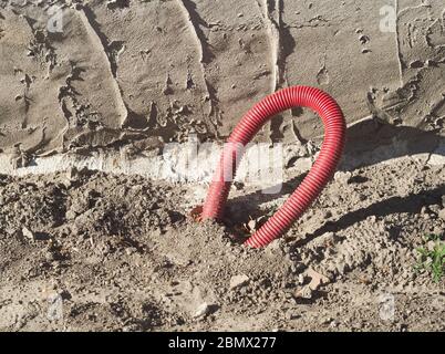 Vergrabene Elektrokabel in roter Kunststoffrohrabdeckung Stockfoto