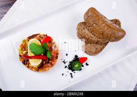 Salat mit Lachs, Kaviar und Rucola auf weißem Hintergrund, mit Grüns und Brotscheiben dekoriert Stockfoto