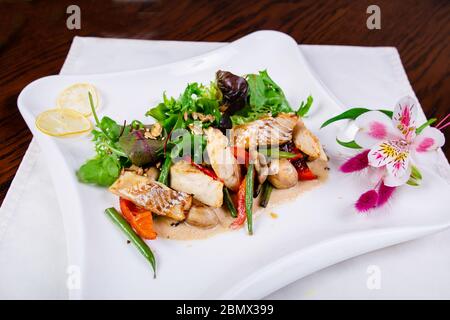 Salat aus Fisch, Pilzen, grünen Bohnen und Paprika auf einem weißen Teller serviert Stockfoto