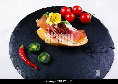 Spanische Tapas. Geröstetes Brot mit Ziegenkäse und serrano-Schinken Stockfoto