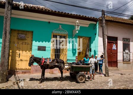 Pferde- und Karren sammeln Müll in einer typischen Kopfsteinpflasterstraße mit bunten Häusern im Kolonialzeitzentrum der Stadt, Trinidad, Kuba Stockfoto