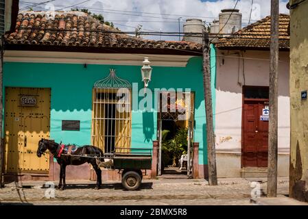Pferd und Wagen vor einem Haus in einer typischen Kopfsteinpflaster Straße mit bunten Häusern im Kolonialzeitzentrum der Stadt, Trinidad, Kuba Stockfoto