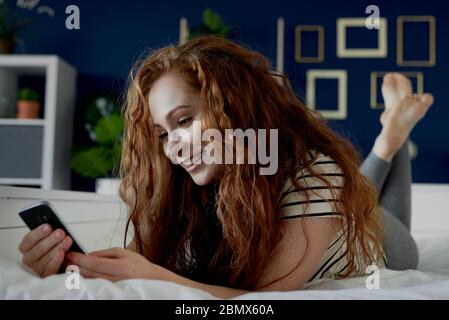 Frau liegt auf dem Bauch und SMS Stockfoto