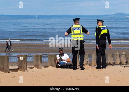 Portobello, Schottland, Großbritannien. 11 Mai 2020. Polizei patrouilliert Promenade und Strand in Portobello heute Nachmittag bei warmem, sonnigem Wetter. Sie sprachen mit der Öffentlichkeit, die am Strand oder an der Meeresmauer saßen und baten sie, sich weiter zu bewegen. Iain Masterton/Alamy Live News Stockfoto