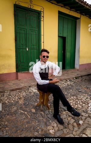 Junger Kellner sitzt vor dem Restaurant im Kolonialzeitzentrum der Stadt, Trinidad, Kuba Stockfoto