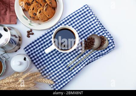 Weiße Tasse Kaffee und hausgemachte runde Plätzchen mit Schokoladenchips. Das Frühstück ist auf dem Tisch. Essen zu Hause. Stillleben. Kaffee und Kaffeebohnen. Ein Stockfoto