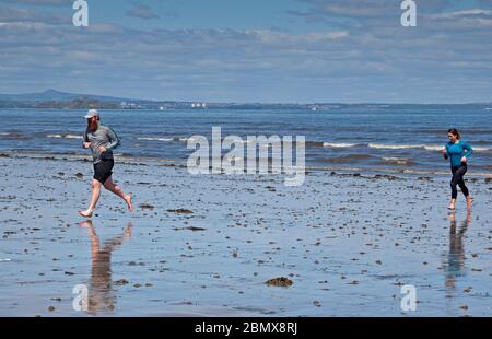 Portobello Beach, Edinburgh, Schottland, Großbritannien. 11 Mai 2020. Junge Paare, die am Meer trainieren, sind froh, dass sie die Möglichkeit haben, mehr als einmal täglich herauszukommen, nachdem die schottische Regierung die Erlaubnis während der Coronavirus-Lockdown gegeben hat. Das Wetter war sonnig mit einer Temperatur von 10 Grad an einem ruhigen Strand mit sehr wenigen Leuten, die dort saßen. Quelle: Arch White / Alamy Live News Stockfoto