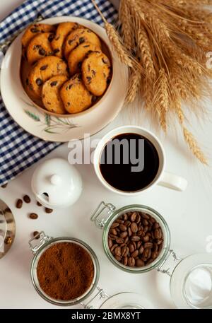 Weiße Tasse Kaffee und hausgemachte runde Plätzchen mit Schokoladenchips. Das Frühstück ist auf dem Tisch. Essen zu Hause. Stillleben. Kaffee und Kaffeebohnen. Ein Stockfoto