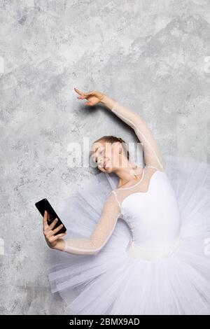 Ziemlich junge Ballerina klassische Ballett-Tänzerin tking Selfie Handy gegen rustikale Wand Stockfoto