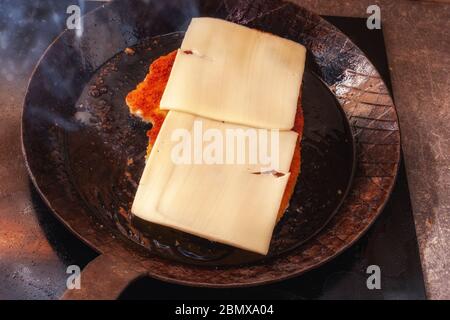 Schnitzel mit Käse in einer handgeschmiedeten Pfanne garen Stockfoto