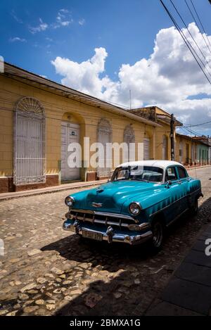 Oldtimer in einer typischen Kopfsteinpflaster Straße mit bunten Häusern in der Kolonialzeit Zentrum der Stadt, Trinidad, Kuba geparkt Stockfoto