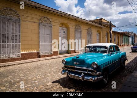 Oldtimer in einer typischen Kopfsteinpflaster Straße mit bunten Häusern in der Kolonialzeit Zentrum der Stadt, Trinidad, Kuba geparkt Stockfoto