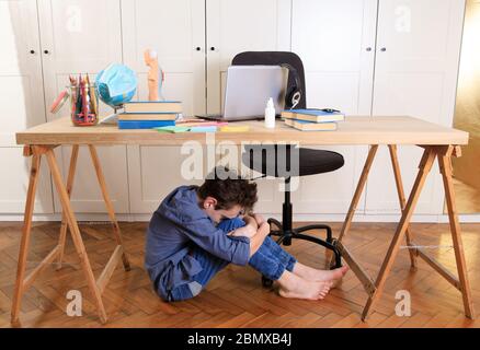 Müde traurig frustrierter Junge, der mit vielen Büchern am Tisch sitzt. Lernschwierigkeiten, Schule, Bildung, Online-Lernen zu Hause Konzept Stockfoto