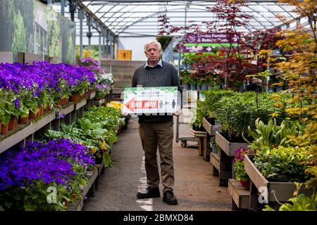 Robin Mercer, Eigentümer von Hillmount Garden Centers, hält ein Schild, das Kunden auf soziale Distanz in seinem Zentrum in Belfast am Stadtrand berät. Herr Mercer hofft, dass Stormont die Sperrung des Coronavirus lockern und der Öffentlichkeit ab Mittwoch den Besuch von Gartencentern ermöglichen wird. Stockfoto