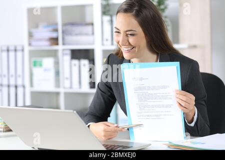 Glückliche Exekutive Frau zeigt Vertrag Unterschrift Raum auf Videocall auf Laptop sitzen auf ihrem Schreibtisch im Büro Stockfoto