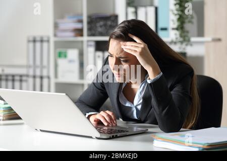 Traurige Geschäftsführerin, die schlechte Nachrichten auf dem Laptop liest und auf ihrem Schreibtisch im Büro sitzt Stockfoto