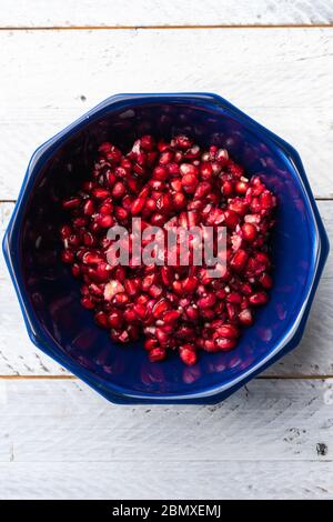 Reife Granatapfel Körner in einer dunkelblauen Schüssel in der Mitte auf einem hellblauen Tisch platziert. Draufsicht Stockfoto