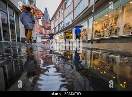 Mainz, Deutschland. Mai 2020. Bei Duschen laufen die Menschen mit Sonnenschirmen durch eine Einkaufsstraße in Richtung Kathedrale. Quelle: Andreas Arnold/dpa/Alamy Live News Stockfoto